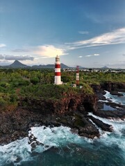 Drone view of Albion Lighthouse, Mauritius at sunset. Stunning coastal scene with golden light, ocean waves, and tropical landscape, perfect for travel and scenic footage.