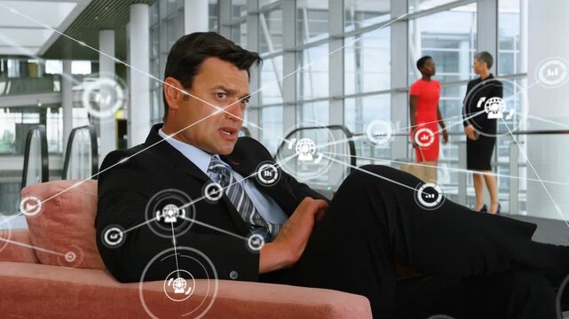 Application icons connecting with lines over caucasian businessman using cellphone on sofa in office