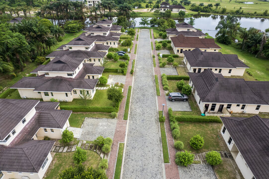 Aerial view of rows of houses stretch towards a tranquil lake under a vast sky, blending modern architecture with nature's serenity, Ibeju Lekki, Lagos, Nigeria.