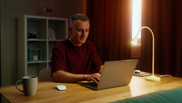 Man remote worker get ready work home. Guy come early morning sit down desk open laptop type keyboard. Male employee surfing net. Busy serious person use pc. Online computer freelancer. Distant job.