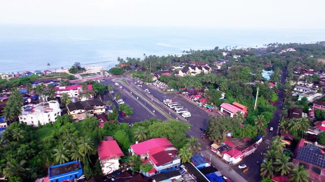 Aerial view of colva beach parking area with road, parked buses, houses and greenery at south goa, india. day time, circle shot, drone shot, 4k.