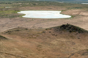 Menschenleere, ausgetrocknete Steppenlandschaft mit See in der Ostmongolei durchzogen von Fahrspuren und Trampelpfaden