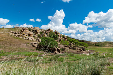 Menschenleere, h&uuml;gelige und schroffe Steppenlandschaft in der Halbw&uuml;ste Gobi in der Mongolei, mit Felsen, Ger&ouml;ll und Gras bei sch&ouml;nem Wetter im Sommer