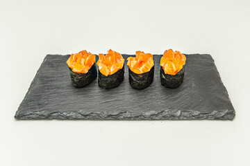 A variety of gunkan maki with different toppings, such as salmon roe, pieces of seafood, or sea urchin, on their compact base of rice.