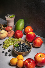 red fruits arranged on a central platter alongside a variety of smoothies (beetroot, watermelon, and raspberry) in tall glasses, with pancakes and maple syrup