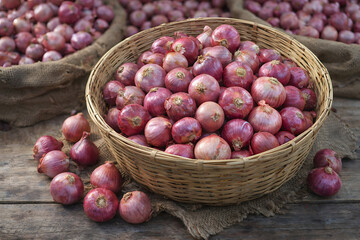 A wicker basket filled with red onions on a wooden table