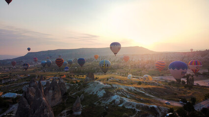 Aerial view of hot air balloons dotting the skyline over the otherworldly landscape of Cappadocia, a symphony of colors against the rising sun., Cappadocia, Turkey.