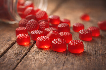 A close-up of red gummy bears spilled out on a wooden surface