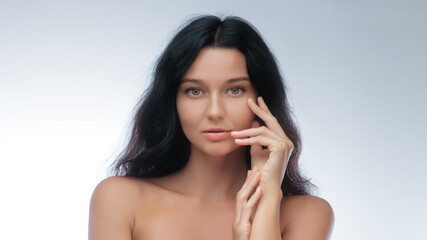 Fototapeta premium Woman With Perfect Skin Touching Face in Soft Studio Light for Skincare Ad