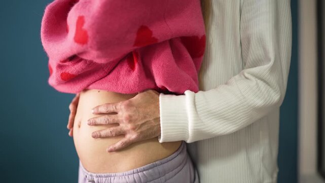 man gently covering a pregnant belly with both hands. The scene expresses emotional support, protection, and deep connection during early pregnancy.