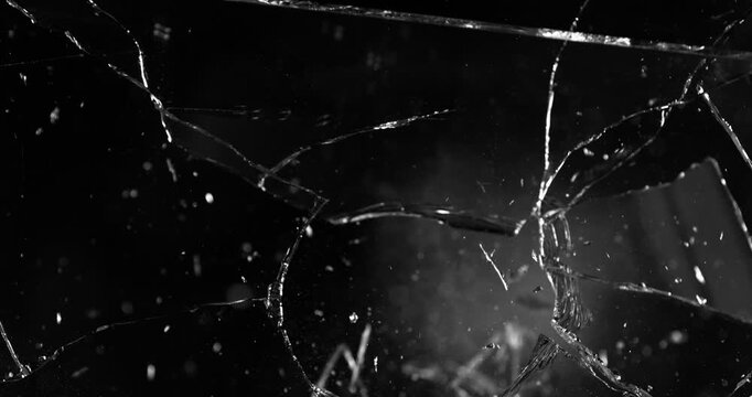 Front view of glass shattered by a bullet in super slow motion (1000fps). Gunshot impact creates cracks, flying shards and dust isolated on black background. Perfect VFX overlay element.