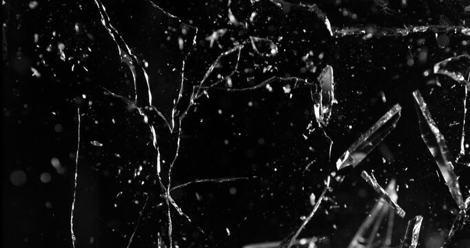 Front view of glass shattered by a bullet in super slow motion (1000fps). Gunshot impact creates cracks, flying shards and dust isolated on black background. Perfect VFX overlay element.