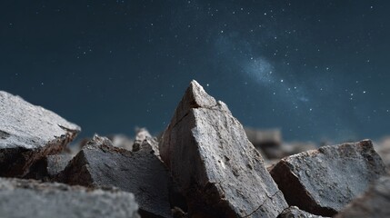 Rugged broken stone fragments in sharp detail against a dark vast night sky filled with stars and a luminous galaxy