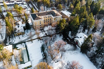 Aerial view of a historic school building surrounded by a winter wonderland, with snow-dusted trees and grounds, showcasing architectural detail and a serene landscape. Obninsk, Russia