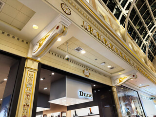 Naklejka premium Ornate shopping arcade facade with gold detailing and modern Dune London storefronts in Manchester, UK