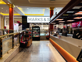 Naklejka premium Shoppers in a Manchester mall browse stores and grab drinks near MarksandSpencer and Starbucks
