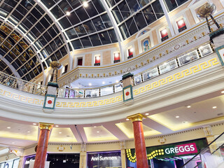Naklejka premium Luxurious Manchester Trafford Centre atrium mall interior with ornate balconies, glass ceiling, and festive Christmas decorations