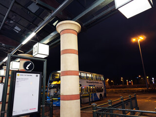 Naklejka premium Bus station at night in Manchester with a double decker bus and illuminated signs