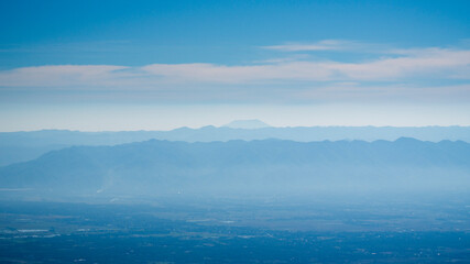 Serene panoramic view of multiple mountain ranges fading into the distance, wrapped in soft blue...