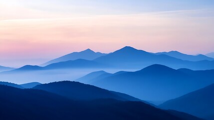 Obraz premium Panoramic view of layered blue mountain ranges under a pastel colored sky