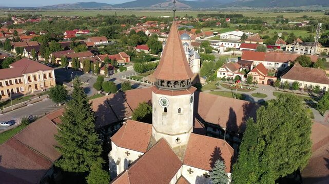 Aerial view of the Fortified church with red roofs contrasting against lush greenery and surrounding buildings, Prejmer, Brasov, Romania.