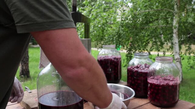 A man makes cherry juice in his garden