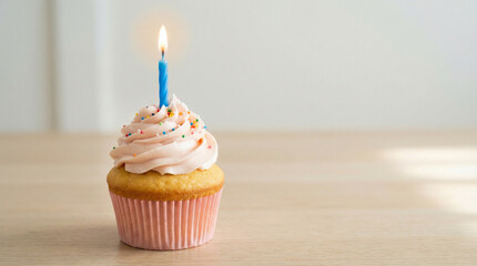 Cupcake with pink frosting and candle on wooden table  