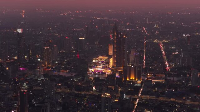 Stunning aerial view of Bangkok's glittering skyline and ICONSIAM major shopping mall at night. Vibrant lights above expansive cityscape