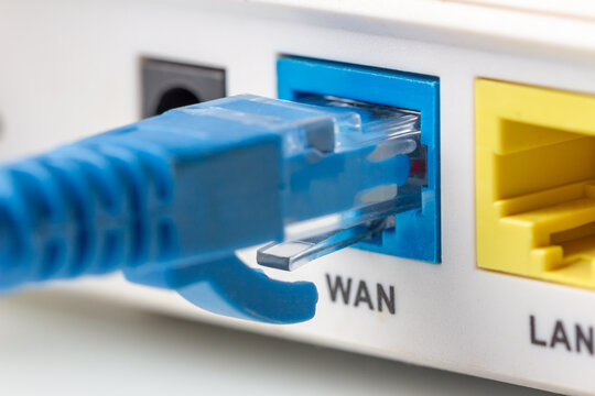 Blue network twisted pair cable connected to the WAN port on the modern wi-fi home router. Close up macro image