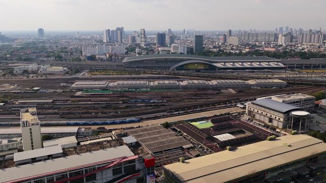 Expansive aerial view of Krung Thep Aphiwat Central Terminal, with multiple railway tracks and Bangkok skyline in the background
