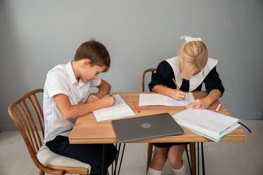 Students Classroom Homework - Two kids in school uniforms are working on their homework at a table.