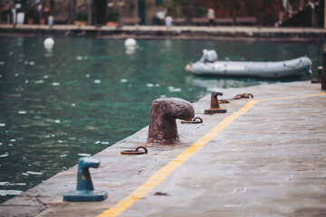 Mooring posts stand on the dock beside calm water. A small boat is tied at the edge. The sky is...