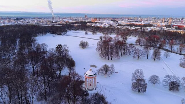 Sonniger Wintermorgen ueber der Muenchner Altstadt. Luftaufnahme vom Monopteros mit Blick auf die historischen Wahrzeichen im Stadtzentrum wie Frauenkirche und Rathaus bei Sonnenaufgang
