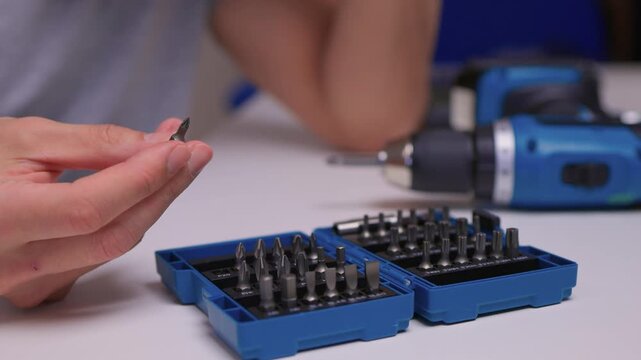 Closeup of hand choosing screwdriver pieces for detailed maintenance, Detailed scene of hand carefully selecting screwdriver bits for fine electronic or furniture repair