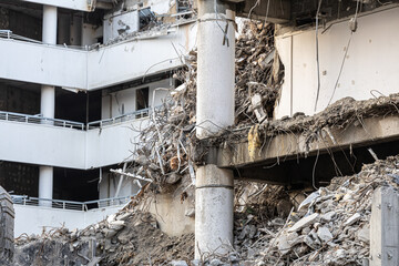 Demolition industry. A heavy-duty yellow hydraulic excavator with a large bucket working on a demolition site of a reinforced concrete building. Old building demolition process.