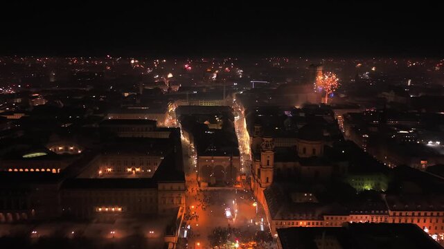 Luftaufnahme aus der Drohne vom naechtlichen Stadtzentrum Muenchens mit Feuerwerk ueber der Altstadt. Beleuchtete Strassen, historische Gebaeude und winterliche Stadtatmosphaere von oben.