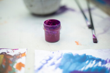A jar of purple paint. A can of paint on the table. Object for drawing.