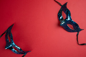 Elegant Blue Sequin Masquerade Masks on a Vibrant Red Background. Copy space