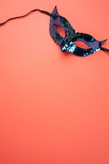 Elegant Sequin Masquerade Mask on Coral Background. Copy space