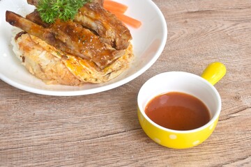 grilled pork rib dressing barbecue sauce with fried cream egg omelet on rice with boiled carrot on plate