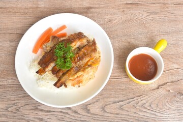 grilled pork rib dressing barbecue sauce with fried cream egg omelet on rice with boiled carrot on plate