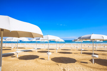 beach with open umbrellas, blue sky