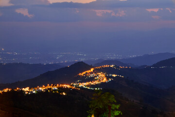 High angle view of illuminated city on mountain peak against sky at night