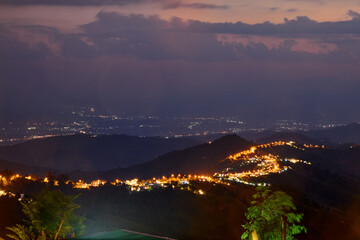 High angle view of illuminated city on mountain peak against sky at night