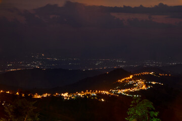 High angle view of illuminated city on mountain peak against sky at night
