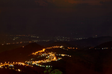 High angle view of illuminated city on mountain peak against sky at night