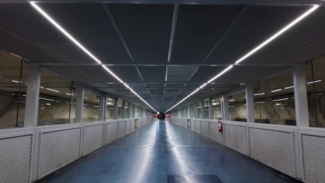 Interior view of the Alicante Airport terminal walkway featuring a blue floor and fluorescent lighting. This modern architecture and travel infrastructure is designed for efficient transportation.