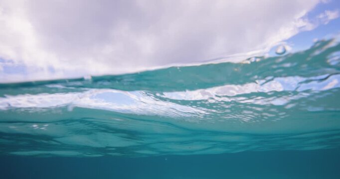 Split-level ocean footage showing both the turquoise water below and dramatic clouds above, capturing the contrast between sea and sky in one frame
