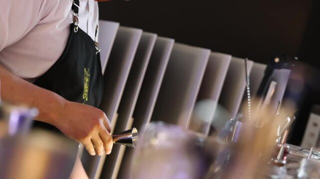 Slow motion refocus shot capturing bartender hands pouring fresh beverages behind a modern bar during an elegant event