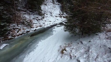 Icy stream in snowy forest mountain landscape creating cold winter nature mood